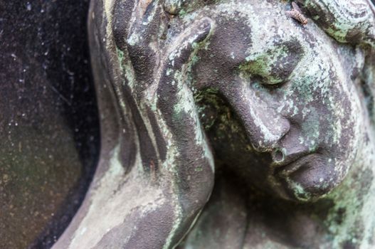 detail of a mourning sculpture on a cemetery