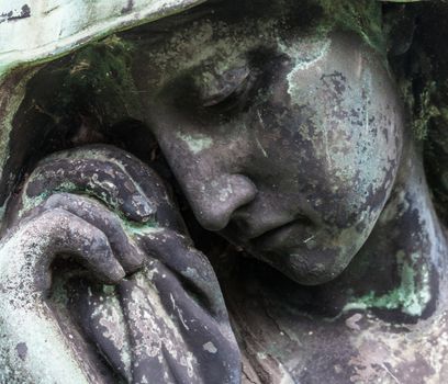 detail of a mourning sculpture on a cemetery