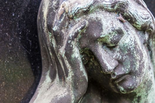 detail of a mourning sculpture on a cemetery