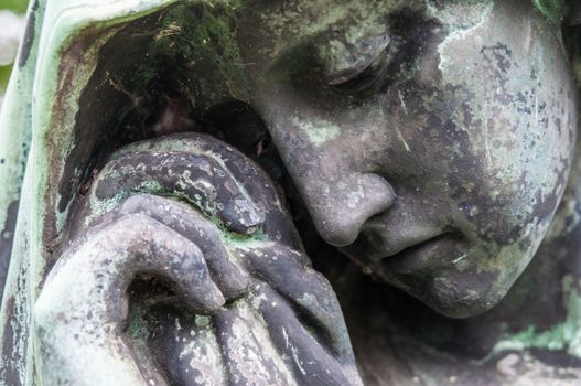 detail of a mourning sculpture on a cemetery