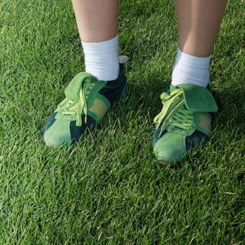 feet of woman dressed in green sports shoes on grass