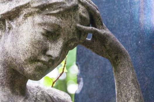 detail of a mourning sculpture on a cemetery