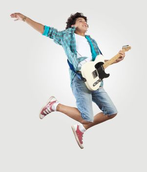 young man playing on electro guitar and jumping