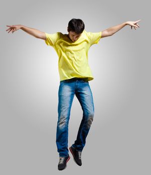 Modern slim hip-hop style man jumping dancing on a grey background