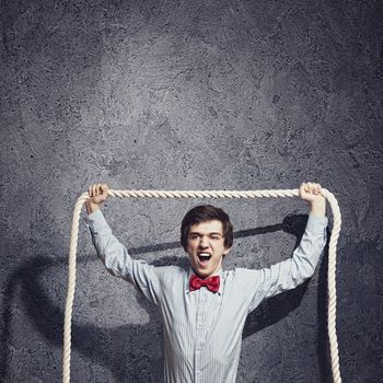 Image of young aggressive businessman holding rope