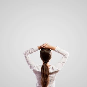 Image of young woman standing with her back with arms above head. Place for text