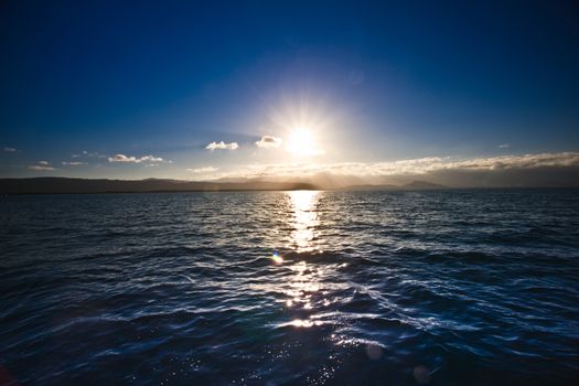 Sun setting over the ocean casting a golden pathway over the surface of the water