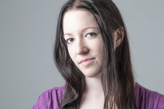 Young woman in purple shirt against a gray background