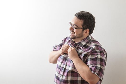 twenty year old man buttoning his shirt against a white all background