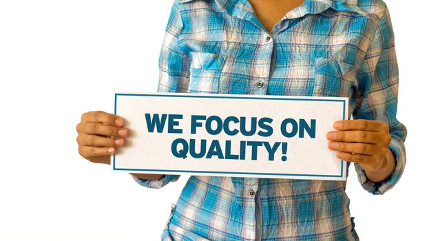A woman holding a We focus on quality sign.
