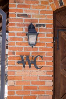 wc toilet sign symbol on red brick wall near retro lighting lamp.