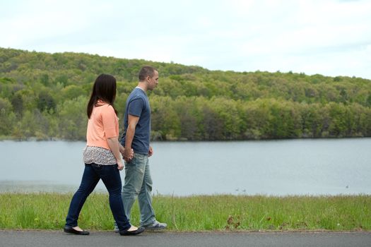 Young happy couple enjoying each others company outdoors walking by the water.