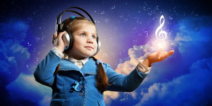 Little cute girl in headphones enjoying music