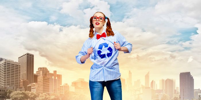 Young woman acting like super hero with recycle sign on chest