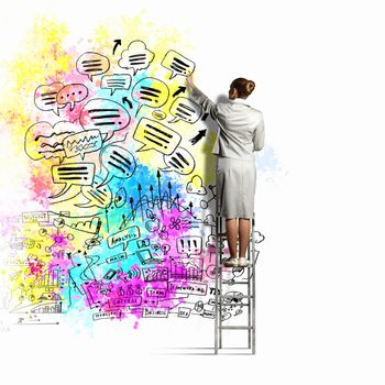 Back view of businesswoman drawing colorful business ideas on wall