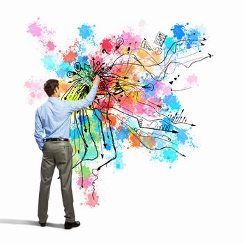 Back view of businessman drawing colorful business ideas on wall