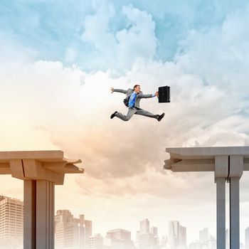 Businessman jumping over a gap in the bridge as a symbol of bridge