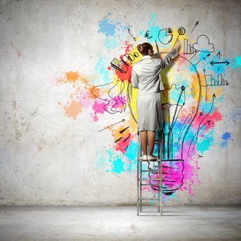 Back view of businesswoman drawing colorful business ideas on wall