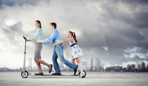 Image of happy young family riding scooter