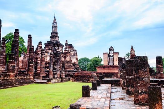 Sukhothai style chedi and standing buddha image in sukhothai historical park, thailand