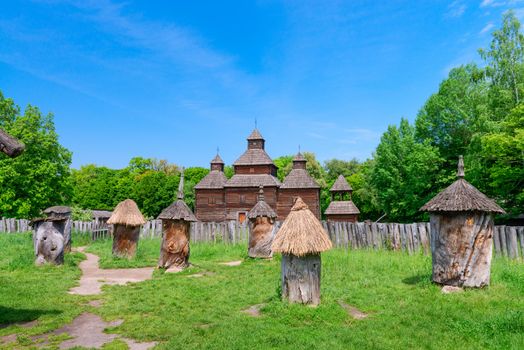 Ancient apiary in wooden bee hive with wooden buildings on background