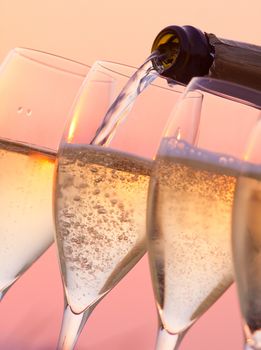 Champagne pouring into glasses with a sunset background