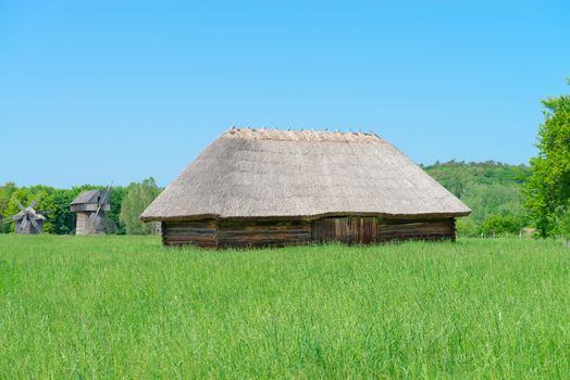 Typical ancient big village shed with straw roof in Ukrainian countryside 