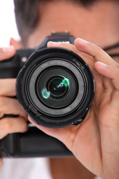 Man focusing his camera with the lens pointed directly at the viewer, close up view