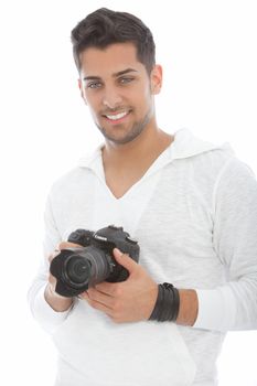 Relaxed professional young male photographer holding his dslr camera, lens and lenshood in his hands, isolated on white