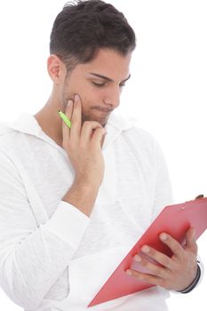 Good looking young man standing reading notes on a clipboard with a thoughtful expression, isolated on white