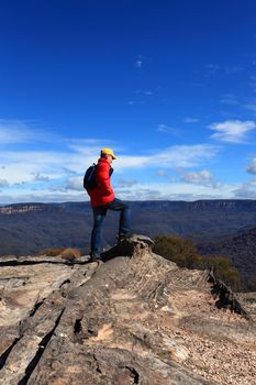 A hiker admires mountain views from Flat Rock Wentworth Falls Australia.