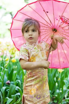 little girl in a kimono with a pink umbrella