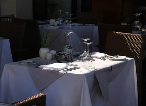 Stylish terrace restaurant table with glasses and cutlery waiting for guests