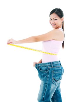 Portrait of an attractive young woman measuring her waist after losing weight over white background.