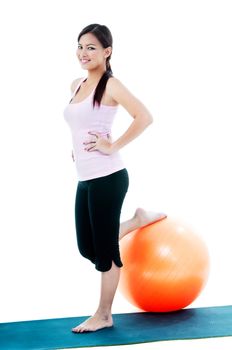 Portrait of a fitness woman standing with one leg on balance ball