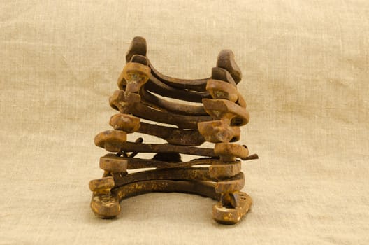 stack pile of old retro rusty horseshoes isolated on linen cloth cloth material background