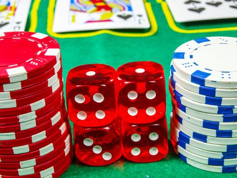 Gambling chips over green table cover with set of cards in the background