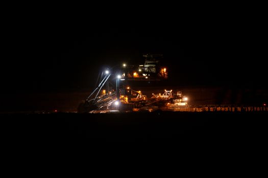 Coal mining in an open pit with huge industrial machine at night shoot