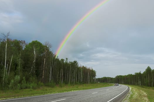 Rainbow after rain over highway in the summer