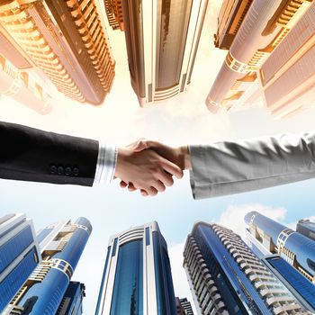 Close up image of hand shake against skyscrapers