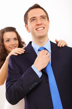 Young businessman dressing at home in the morning. Woman helping to fasten his tie