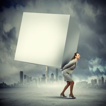 Image of businesswoman carrying big white cube on her back. Place for text