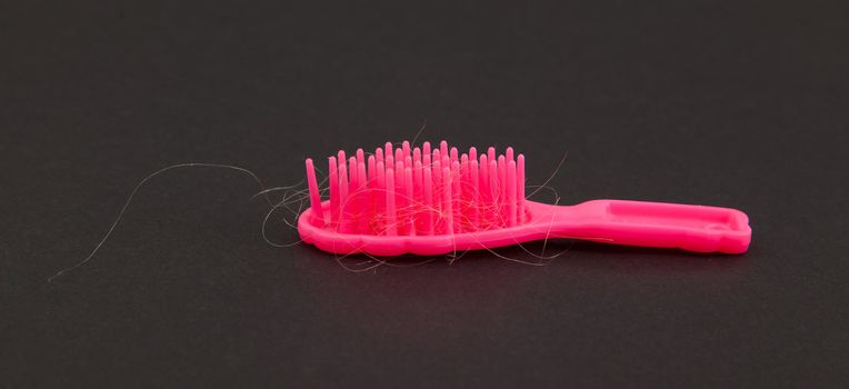 Pink toy brush with hair isolated on black