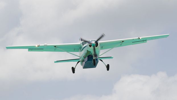 Small plane descending against a cloudy sky