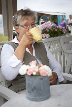 A retired pensioner sitting in a cafe having a coffee