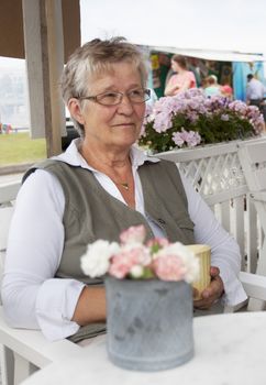 A retired pensioner sitting in an outdoor cafe having a coffee