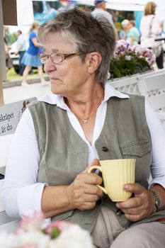 Retired pensioner woman sitting in an outdoor cafe