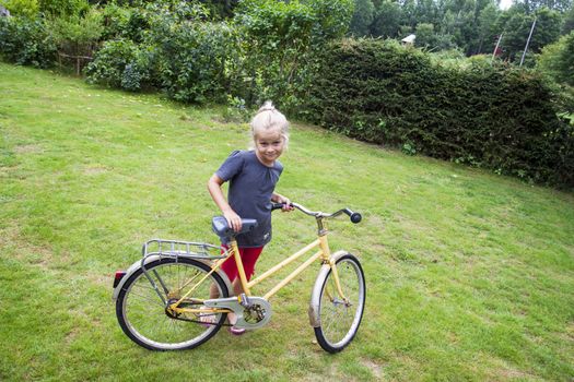 A small girl learning to ride a bike. positive feeling