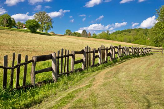 Wooden fence in green landscape under blue sky