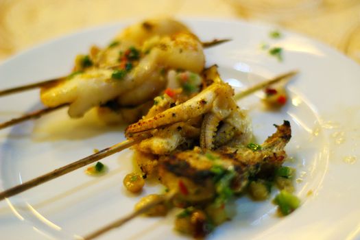 Baby octopus with coriander and basil pesto grilled on skewers in a restaurant in Nha Trang, Vietnam. Sea food is a popular local specality.